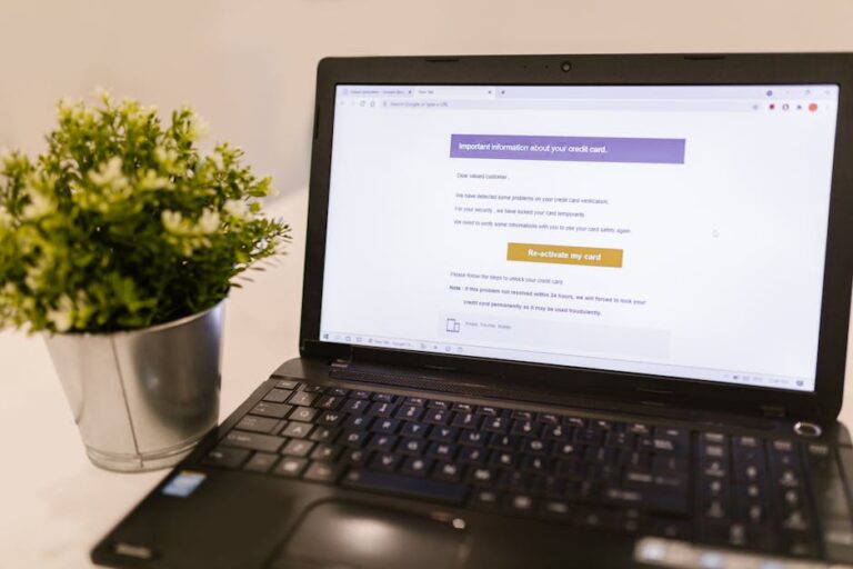 Laptop showing a bank statement style financial document on a bright office desk — reviewing recurring digital expenses